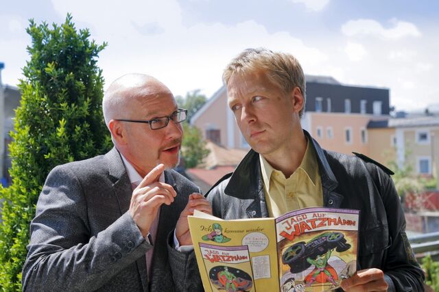 Die Rosenheim-Cops – Mit Hilfe des wiedergefundenen Comics bringt Experte Thomas Thiel (Marcus Calvin, l.) Polizist Mohr (Max Müller, r.) auf eine heiße Spur.