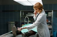 Rentnercops – Rechtsmedizin – Dr. Schmidt (Helene Grass) telefoniert und nimmt nebenbei die Leiche oberflächlich in Augenschein.