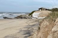 Re: – Das Dorf Apúlia ist in Gefahr: Die Häuser auf der Düne müssen im Winter vor der Flut geschützt werden.