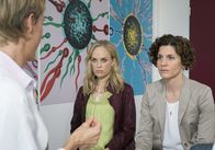 Vier kriegen ein Kind – Die Gynäkologin Gesche (Theresa Berlag, li.) offenbart Steff (Friederike Kempter, Mitte) und Neele (Christina Hecke), dass es bei der künstlichen Befruchtung zu einem folgenschweren Fehler gekommen ist.