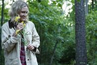 Tödliche Stille – A woman happily walks through the woods with flowers.