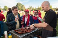 Leberkäsjunkie – ARD Degeto LEBERKÄSJUNKIE Uhr im ERSTEN. Die Fans von Rot-Weiß Niederkaltenkirchen stehen Schlange, um bei Metzger Simmerl (Stephan Zinner, re.) eine Wurst zu ergattern: Dorfpolizist Franz Eberhofer (Sebastian Bezzel, li.), der Bürgermeister (Thomas Kügel, 2. v. li.) und Heizungspfuscher Flötzinger (Daniel Christensen, 2. v. re.)