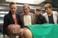 Rentnercops – Dr. Rosalind Schmidt (Helene Grass, rechts) teilt Vicky (Katja Danowski, links), Günter (Wolfgang Winkler, 2. von links) und Edwin (Tilo Prückner) das Ergebnis der Obduktion mit. Connor Taylor (Roy Wesche, vorne) ist an einem Herzinfarkt gestorben.