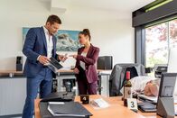 Die Rosenheim-Cops – Pathologin Atay (Sevda Polat, M.) weist Kommissar Hansen (Igor Jeftić, l.) darauf hin, dass dem Rotwein, den das Opfer (Komparse, r.) getrunken hatte, vermutlich eine toxische Substanz beigemischt wurde.
