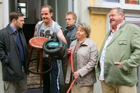 Die Rosenheim-Cops – Die Cops (Mark-Alexander Solf, l.; Joseph Hannesschläger, r.; Max Müller, m.) fahren zur Wohnung des Opfers und treffen auf Hausmeister Rosenmüller (Johannes Steck, 2.v.l.) und Nachbarin Käthe Haase (Sarah Camp, 2.v.r.).