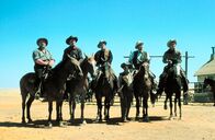 Weites Land – Die Harmonie wird durch die hasserfüllte Dauerfehde von Major Terrill (Charles Bickford, Mitte) gegen Viehzüchter Rufus Hannassey (Burl Ives, links) getrübt. Beide versuchen seit Jahren, eine wichtige Wasserstelle unter ihre Kontrolle zu bekommen. (Buck Hannassey (Chuck Connors, 2. von links), Vormann Steve (Charlton Heston, 1. von rechts) und James McKay (Gregory Peck, 2. von rechts).