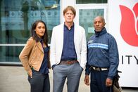 Death in Paradise – Der Polizist Humphrey (Kris Marshall, m.) ist mit seinen zwei Kollegen Dwayne (Danny John-Jules, r.) und Florence (Josephine Jobert, l.) von der Karibik nach England gereist, um einen Mordfall aufzuklären. In England ist nun eine zweite Leiche gefunden worden. Humphrey glaubt, dass die zwei Morde zusammen hängen.