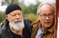 Rentnercops – Reinhard Bielefelder (Bill Mockridge, l.) und Klaus Schmitz (Hartmut Volle, r.) beobachten aus einem Versteck heraus Naumann, der offensichtlich in Schwierigkeiten steckt.