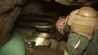 Amerikas heiße Grenze – Nogales, AZ: An armed agent looking back while going through an underground tunnel. Armed with just a handgun, agents can barely squeeze through the claustrophobic passage.