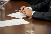 WELT Live – Ein Politiker im Anzug sitzt während einer Diskussion an einem polierten Holztisch vor einem Mikrofon