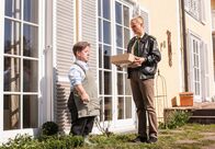 Hubert und Staller – Kunkel (Hans Peter Luppa, links) ist mit einer Gartenhacke in einem Beet vor Megans Fenster zugange, er entfernt einige niedergetrampelte Zweige. Sonja (Annett Fleicher, rechts) kommt mit dem Paket dazu.