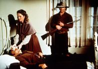 Unsere kleine Farm – Nach einem Überfall auf die Blindenschule beobachtet Bandenchef Jake (James McIntire, r.), wie Mary Kendall (Melissa Sue Anderson, M.) sich um seinen verletzten Kumpan Abel (Larry Golden, liegend) kümmert.