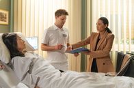 In aller Freundschaft – Dr. Lilly Phan (Mai Duong Kieu, re.) hat ihrer Mutter Hoa (Akiko Hitomi, li.) ihren Freund Kris Haas (Jascha Rust, mi.) bisher verschwiegen. Als sie Kris im Zimmer ihrer Mutter vorfindet, ist sie ziemlich harsch zu ihm.