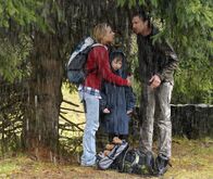 Der Bergdoktor – Ein heftiges Gewitter und ein Wolkenbruch gehen über der Berglandschaft nieder. Susanne (Natalie O'Hara, l.), Jonas (Fabian Elias Huber, m.) und Hans (Heiko Ruprecht, r.) flüchten unter einem großen Baum, der sie aber wenig vor dem Regen schützt.