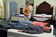 The Middle – Frankie (Patricia Heaton, in der Mitte liegend) ist begeistert, als Mike (Neil Flynn, vorne liegend) zustimmt, mit ihr ein neues Bett zu kaufen. Dabei lassen sie sich gern von einem Verkäufer (Jon Paul Burkhart, stehend) beraten. Da kommt Mike jedoch plötzlich auf die Idee, selbst ein Bett zu bauen ...