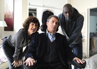 Ziemlich beste Freunde – Driss (Omar Sy, re.) und Yvonne (Anne Le Ny) putzen Philippe (François Cluzet) heraus.
