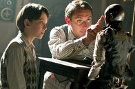 Hugo Cabret – Hugo Cabret (Asa Butterfield, li.) hat schöne Erinnerungen an seinen Vater (Jude Law, Mi.), der Uhrmacher war, – etwa, wie der Vater einen Automatenmenschen repariert, den er später an Hugo vererbte.