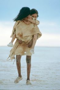 Long Walk Home (ARTE) (100% Drama) (100% Drama) (100% Haus & Garten) – Molly (Everlyn Sampi, vo.) trägt ihre erschöpfte Schwester Daisy (Tianna Sansbury, hi.) tapfer durch den australischen Outback.