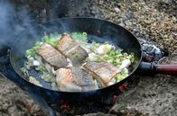 Zu Tisch ... – Sein festes und mageres Fleisch macht ihn zu einer Delikatesse: Skrei-Filet mit Frühlingszwiebeln – gebraten auf offenem Feuer am Strand.