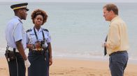 Death in Paradise – JP Hooper (Tobi Bakare, l.) und Ruby Patterson (Shyko Amos, M.) berichten DI Jack Mooney (Ardal O'Hanlon, r.) von den neuesten Erkenntnissen.