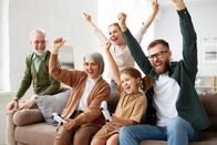 111 – Crazy weekend. Excited big multi generation family, grandparents, mother and father and little kids playing video games while sitting on couch in living room, having fun and enjoying time together