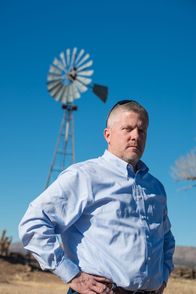 Airplane Repo - Die Inkasso-Piloten – Ken Cage in front of a windmill.