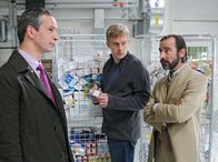 Tatort – SWR Fernsehen TATORT, "Im Sog des Bösen" Uhr. Perlmann (Sebastian Bezzel, Mitte) ist überzeugt, dass der Mord etwas mit dem illegalen Handel mit Medikamenten zu tun hat und die Herren Sardis (Thomas Dannemann, li.) und Nohberg (Henry Meyer, re.) wiederum mit dem illegalen Handel. Aber als beurlaubter Polizist hat er schlechte Karten bei der Befragung.