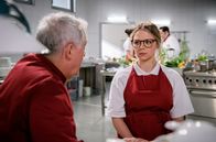 Sturm der Liebe – André (Joachim Lätsch, l.) versucht, Josie (Lena Conzendorf, r.) von ihrem Vorhaben den "Fürstenhof" zu verlassen, abzuhalten (mit Kompars:innen).