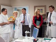 In aller Freundschaft – Hans-Peter Brenner (Michael Trischan, li.) bereitet seinen Vorgesetzten Dr. Roland Heilmann (Thomas Rühmann, mi.), Dr. Kathrin Globisch (Andrea Kathrin Loewig, 2.v.li.) und Dr. Martin Stein (Bernhard Bettermann, re.) sowie Verwaltungschefin Sarah Marquardt (Alexa Maria Surholdt, 2.v.re.) mit selbstgestalteten Eiern eine ganz besondere Osterfreunde.