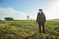 Wild Bill – Bill Hixon (Rob Lowe) steht in seiner Uniform auf einer grünen Wiese. Weit und breit ist sonst niemand zu sehen.