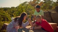 Campsite – Wer sagt, dass Mädchen schwächer sind? Lea (Sophia Haug Khoury, links) fordert ihren Stiefbruder Theo (Herman Nysæther Grinde, rechts) zum Armdrücken heraus. Nura (India Dee Kvangarsnes) schaut zu.