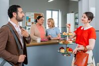 Die Rosenheim-Cops – Bevor die Konditorin Ines Schäfer (Anuschka Tochtermann, r.) mit Controller Donato (Paul Brusa, l.) ihren Businessplan bespricht, präsentiert sie Frau Grasegger (Ursula Maria Burkhart, 2.v.l.) und Frau Lange (Sarah Thonig, 2.v.r.) ihre Patisserien.