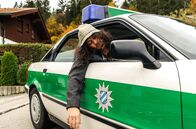 Hubert ohne Staller – Der Oktoberfest-Tourist Spyros Karamanlis (Nikos Laskaris) ist stark betrunken und wird im Polizeiauto zu seiner Unterkunft gebracht.