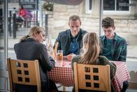 The Bay – Lisa Armstrong (Morven Christie, l.v.) und ihre beiden Kinder Rob (Art Parkinson, r. h.) und Abbie (Imogen King, r.v.) treffen sich gemeinsam mit Andy Warren (Joe Absolom, l.h.) in einem Restaurant. Das Familienglück täuscht jedoch.