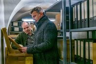 Der Bergdoktor – Im Ellmauer Archiv stellt Martin (Hans Sigl, r.) mit Hilfe von Herrn Hanselbauer (Matthias Kupfer, l.) Nachforschungen zum mysteriösen Mooserhof an.