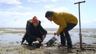 Deutschlands Naturwunder – Biologin Dr. Svenja Reents und Wissenschaftsjournalist Niklas Kolorz entnehmen eine Bodenprobe, um die beeindruckende Artenvielfalt des Wattbodens nachzuweisen.