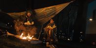 Totem – Ama (Amani-Jean Philippe) und ein Griot (Kenneth Herdigein), sitzen am Lagerfeuer, wärmen sich und essen Fisch. Der Griot erzählt Ama Geschichten über Totem-Tiere.