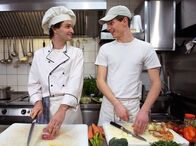 In aller Freundschaft – Jakob (Karsten Kühn, rechts) kann in Freddys (Luca Zamperoni) Küche etwas in die Arbeit eines Kochs reinschnüffeln. Das gefällt ihm so gut, dass er gern ein Praktikum im "Charlotto" machen würde.