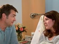 In aller Freundschaft – Dr. Elena Eichhorn (Cheryl Shepard) liegt mit dem Verdacht auf Malaria Tropica in der Sachsenklinik. Ihr Freund Valentin Hoppe (Stefan Gubser) sitzt besorgt an ihrem Bett.