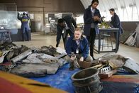 Mayday - Alarm im Cockpit – RE-CREATION: Tom Haueter (played by Danny Deakin) picks up a piece of debris while other investigators (played by background performers) look at other pieces from the wreckage.   (photo credit: Cineflix/Ian Watson)