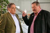 Die Rosenheim-Cops – Gegenüber Hofer (Joseph Hannesschläger, r.) spielt Bräutigamsvater Fichtner (Gerd Udo Feller, l.) den Streit mit dem Opfer herunter.