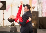 Agatha Raisin – Da Agatha Raisin ihre Tanzvorstellung kurzfristig abbrechen muss, um zu ermitteln, schickt sie Roy Silver (Mathew Horne, r.) auf die Bühne, der nun etwas verwirrt den Tango mit George Felliet (Adam Garcia, l.) zu Ende tanzen muss.