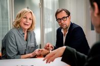 Kroymann – In "Kroymann", Folge 13, freuen sich prominente Homosexuelle (Maren Kroymann, links) über Agenturen, die Alibi-Eheleute (Jan Josef Liefers, rechts) vermitteln.