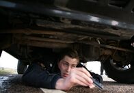 Mankells Wallander – Pontus (Sverrir Gudnason) hat sich unter dem Polizeiwagen versteckt und filmt einen Raubüberfall mit dem Handy.