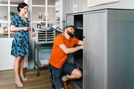 Die Rosenheim-Cops – Paketbote Hannes Winkler (Steffen Wolf, r.) versucht, den Aktenschrank im Büro von Miriam Stockl (Marisa Burger, l.) zu reparieren.