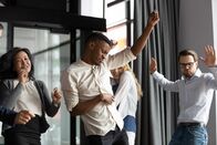 111 – Excited happy multiracial businesspeople have fun engaged in activity in office together, overjoyed diverse colleagues dance celebrate successful business project, Friday celebration concept