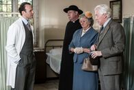Father Brown – Dr. Joseph Ashley (David Sturzaker, l.) versucht Father Brown (Mark Williams, 2.v.l.), Mrs. McCarthy (Sorcha Cusack, 2.v.r.) und den besorgten Vater William Bayley (Nick Dunning, r.) zu beruhigen. Noch wissen sie nicht, weshalb Charlotte krank ist, doch Dr. Ashely ist zuversichtlich, dass sie wieder gesund wird.