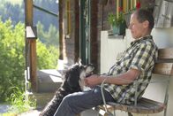 Ich, Bauer – Jakob Schabernig sitzt vor seinem Hof mit Hund