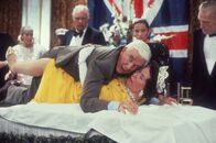 Die nackte Kanone – Der ungeschickte Lt. Frank Drebin (Leslie Nielsen, oben) versucht ein Attentat auf die britische Königin Elizabeth II. (Jeannette Charles, unten) zu vereiteln.