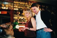 Kommissar Rex – Nach getaner Arbeit führt Kommissar Brandtner (Gedeon Burkhard, r.) seine attraktive Kollegin Nina Wallentin (Eva Herzig, l.) in eine Bar aus. Rex präsentiert eine Rose ...